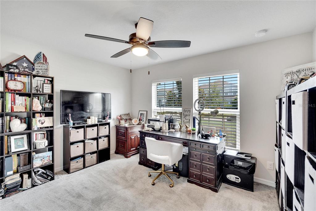 A home office features a desk, shelving units, a television, and a ceiling fan — 11355 LELAND GROVES DRIVE, RIVERVIEW, FL