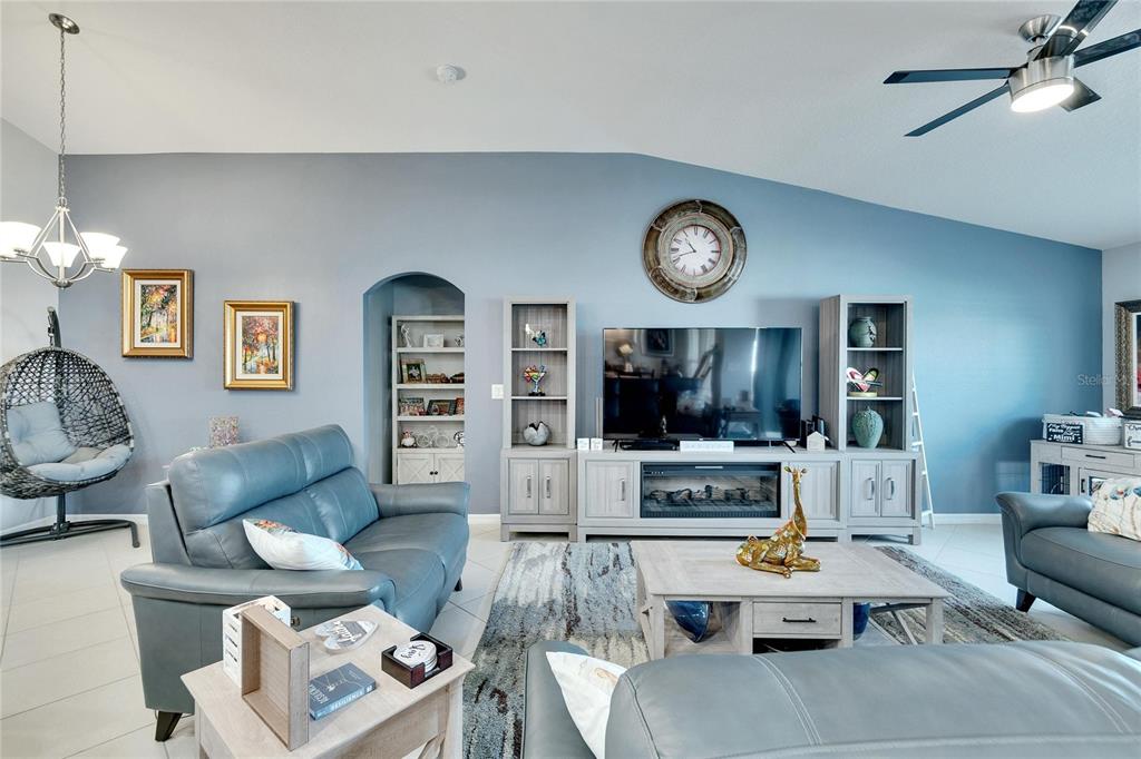 A living room features blue walls, a gray leather sofa, and a television media console — 11355 LELAND GROVES DRIVE, RIVERVIEW, FL