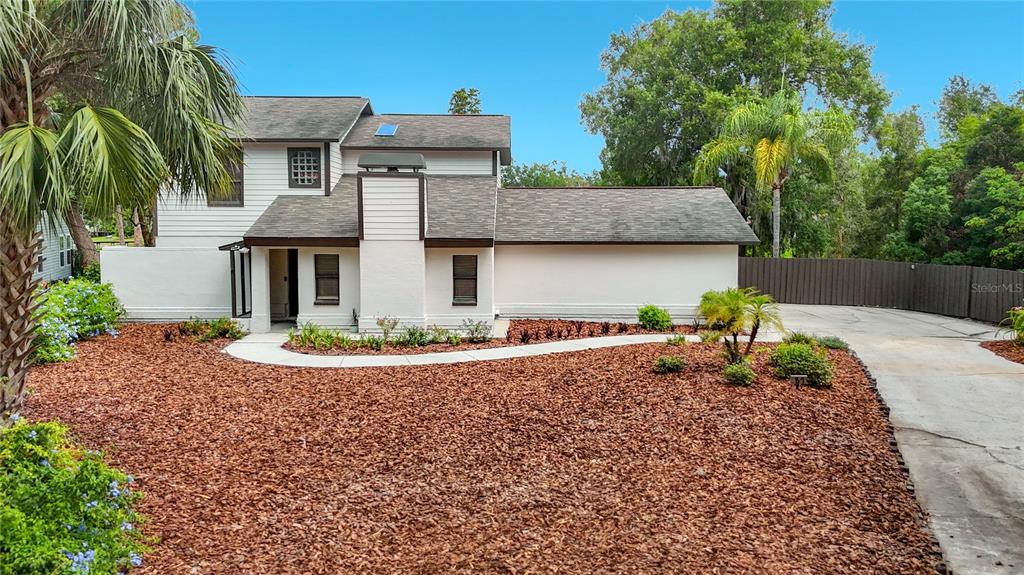 A two-story house with white siding, a brown shingled roof, and a large mulch front yard — 87 1ST AVENUE NW, LUTZ, FL