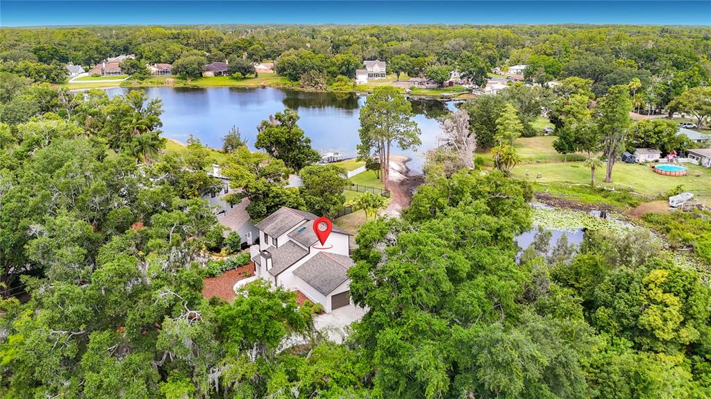 An aerial view shows a two-story house with a red location pin near a lake — 87 1ST AVENUE NW, LUTZ, FL