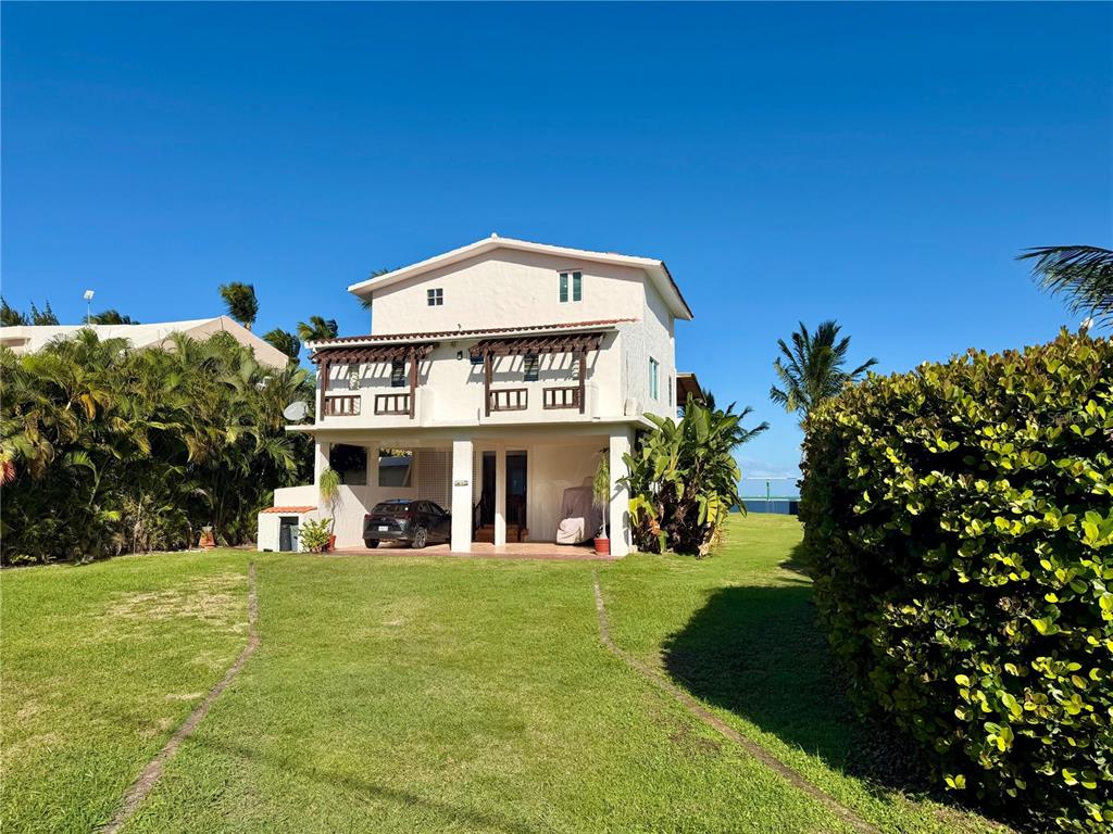 A two-story house with a balcony and a ground-level carport sits on a grassy lawn — 968 CAMINO LAS PICUAS UNIT 14, RIO GRANDE, PR