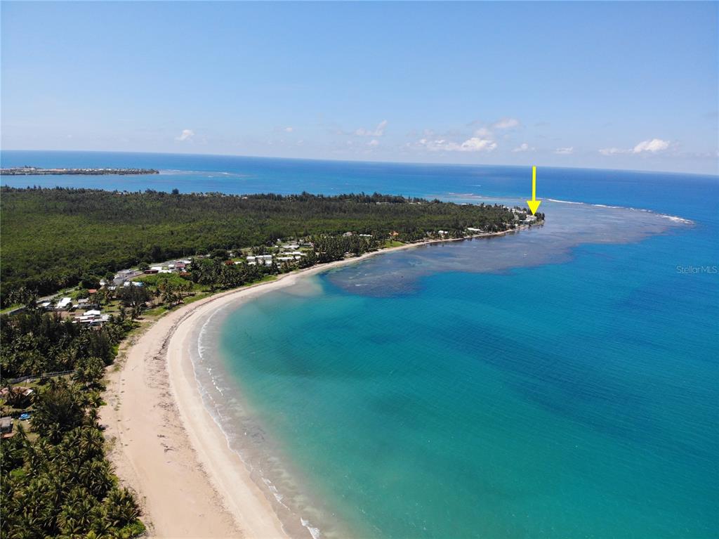 An aerial view shows a sandy beach along a coastline with a yellow arrow pointing toward a building — 968 CAMINO LAS PICUAS UNIT 14, RIO GRANDE, PR