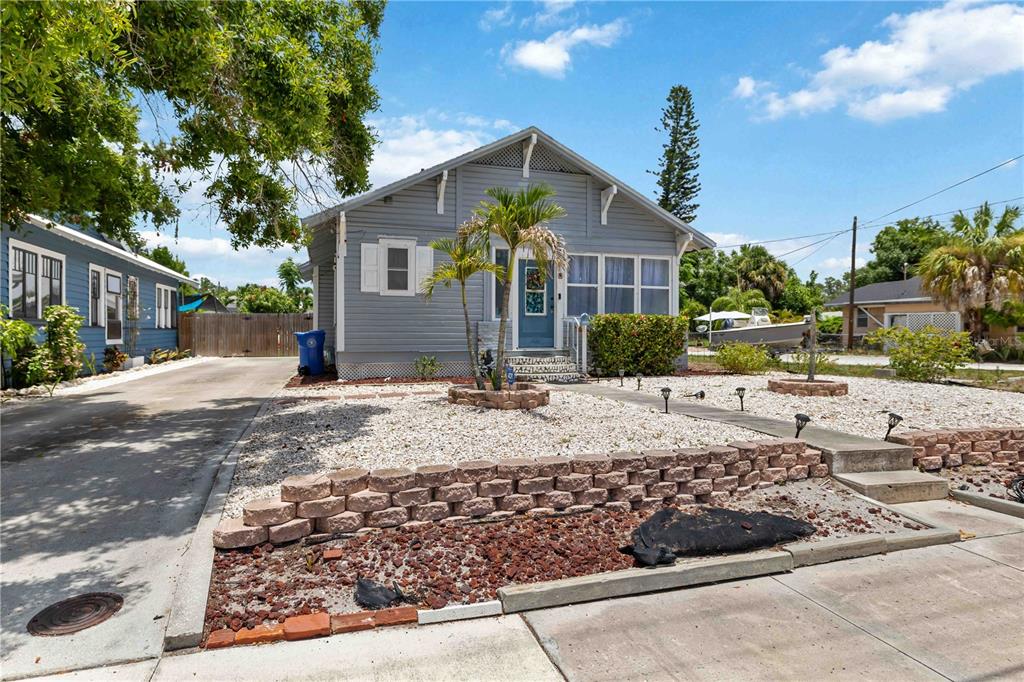 A light blue, single-story house with a front porch, gravel yard, and concrete driveway — 2314 7TH AVENUE W, BRADENTON, FL
