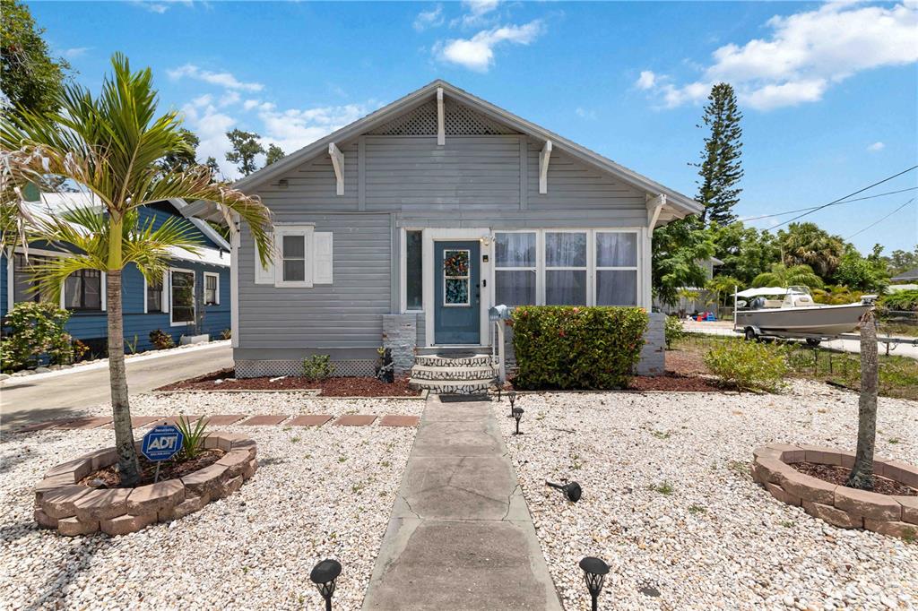 A gray, single-story bungalow with a front porch, gravel yard, and a palm tree — 2314 7TH AVENUE W, BRADENTON, FL