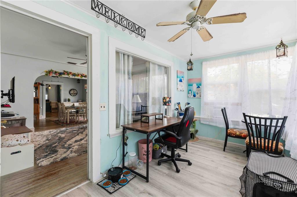 A sunroom features light blue walls, wood-look flooring, a ceiling fan, and a desk area — 2314 7TH AVENUE W, BRADENTON, FL