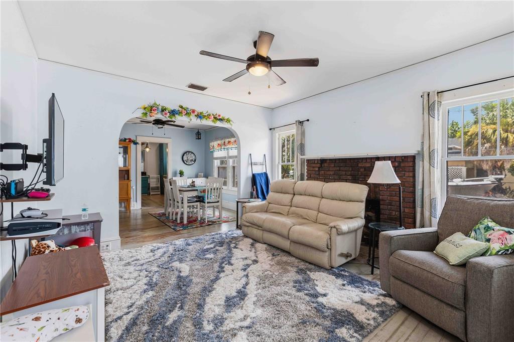 A living room features a brick fireplace, a ceiling fan, and an arched entryway — 2314 7TH AVENUE W, BRADENTON, FL