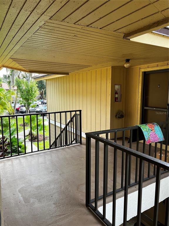An exterior view of a covered apartment balcony with black railings and yellow siding — 120 HIBISCUS WOODS COURT UNIT 11B, DELTONA, FL
