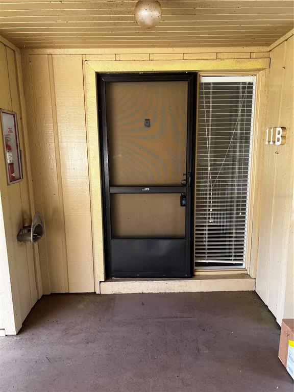 An exterior view of a residential entrance with a screen door and a window — 120 HIBISCUS WOODS COURT UNIT 11B, DELTONA, FL
