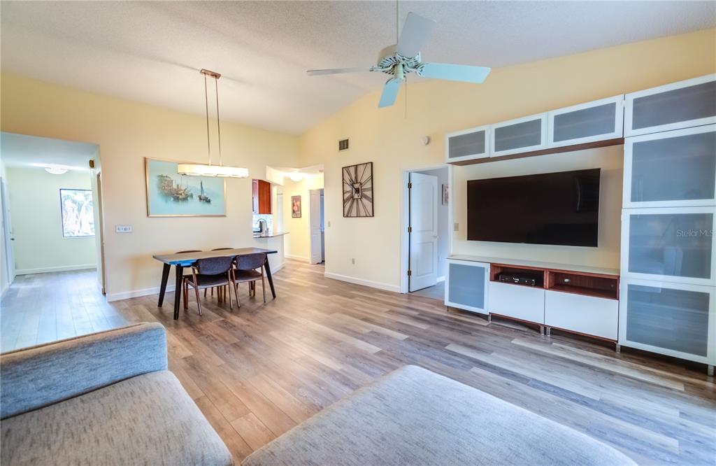 A living room and dining area feature light wood-look flooring, a ceiling fan, and cabinetry — 600 CARRIAGE HOUSE LANE UNIT 201, NOKOMIS, FL