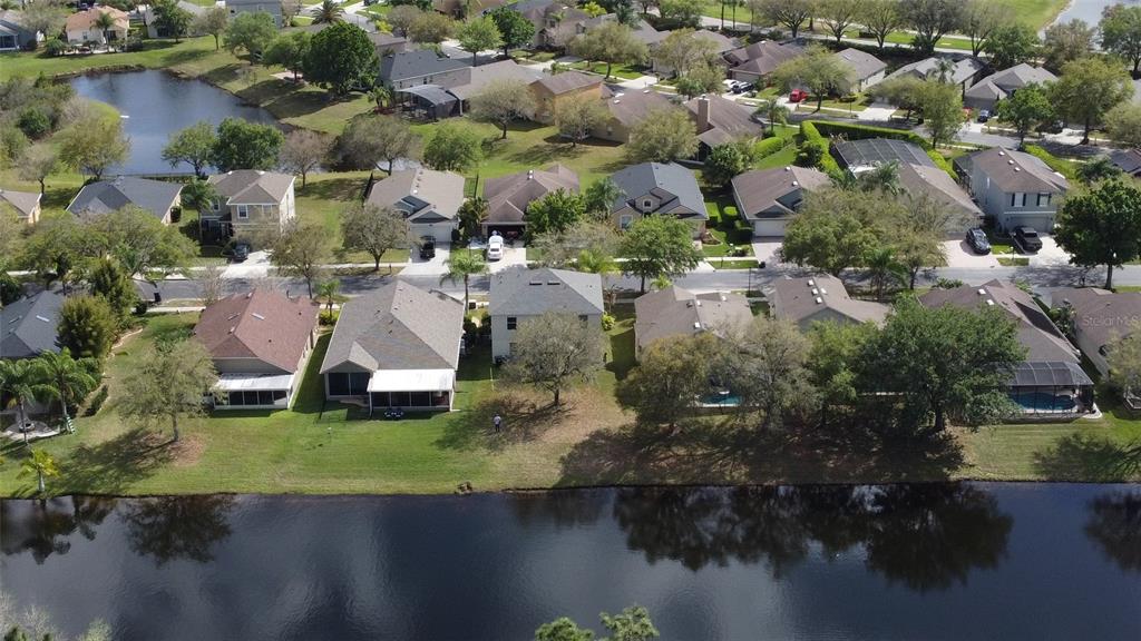 An aerial view shows a suburban neighborhood with houses bordering a large pond — 2264 HILLSHIRE DRIVE, ORLANDO, FL