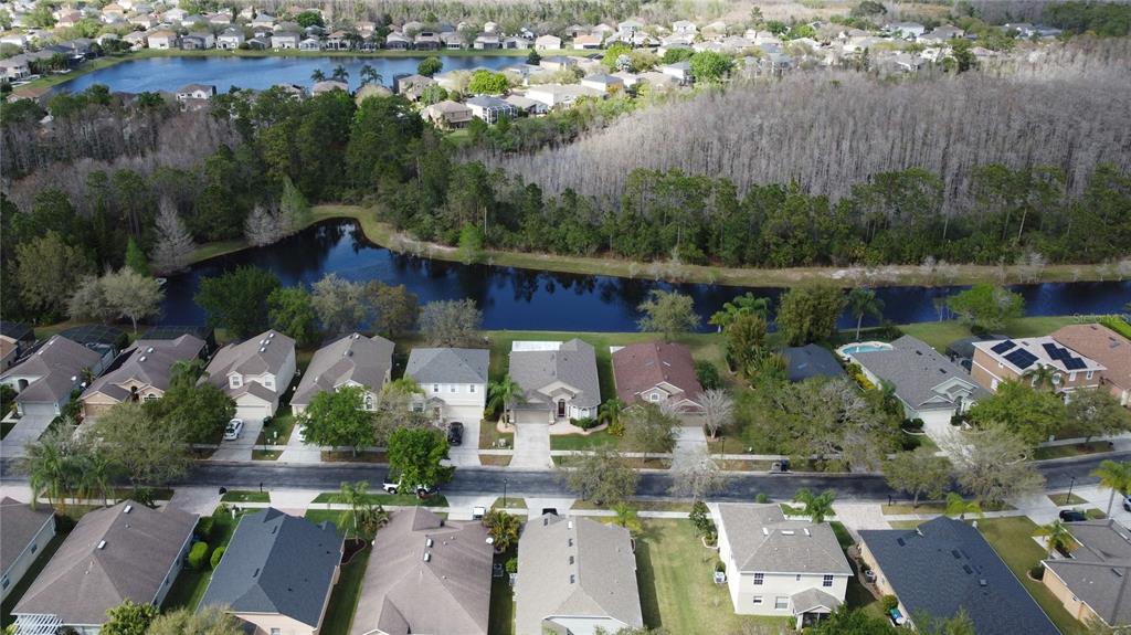 An aerial view shows a suburban neighborhood with houses bordering a pond and woods — 2264 HILLSHIRE DRIVE, ORLANDO, FL