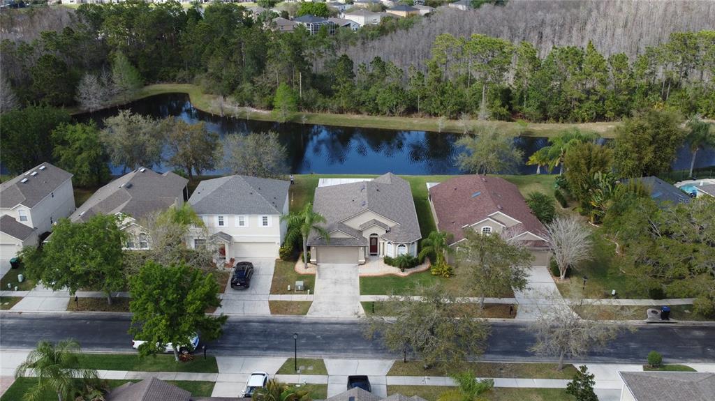 An aerial view shows a row of suburban houses situated along a pond and wooded area — 2264 HILLSHIRE DRIVE, ORLANDO, FL