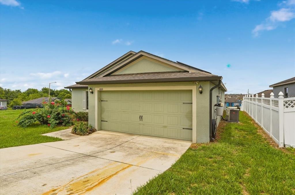 A single-story house exterior features a light green garage door and a concrete driveway — 1603 ELLINGTON DRIVE, DUNDEE, FL