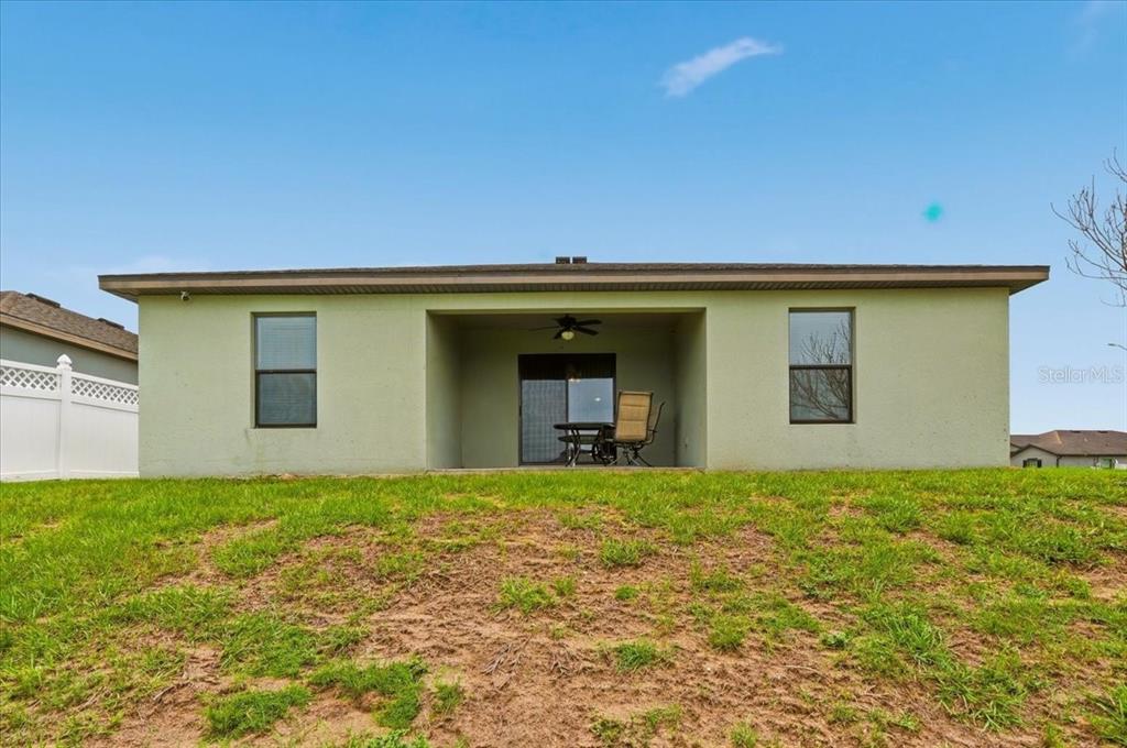 The rear exterior of a single-story house features a covered patio and a grassy yard — 1603 ELLINGTON DRIVE, DUNDEE, FL
