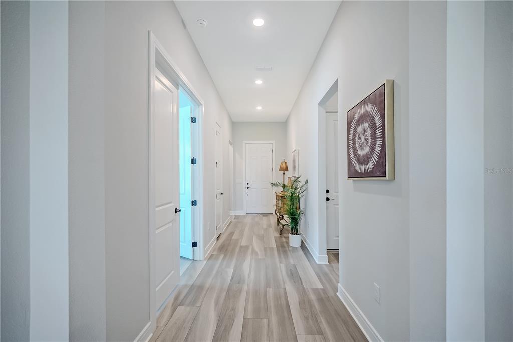 A hallway with light wood-look flooring, white walls, recessed lighting, and several interior doors — 8718 SW 59TH LANE ROAD, OCALA, FL
