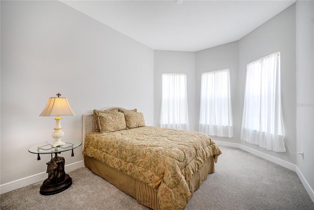 A bedroom features a bed with a patterned comforter, a glass-topped side table, and windows — 8718 SW 59TH LANE ROAD, OCALA, FL