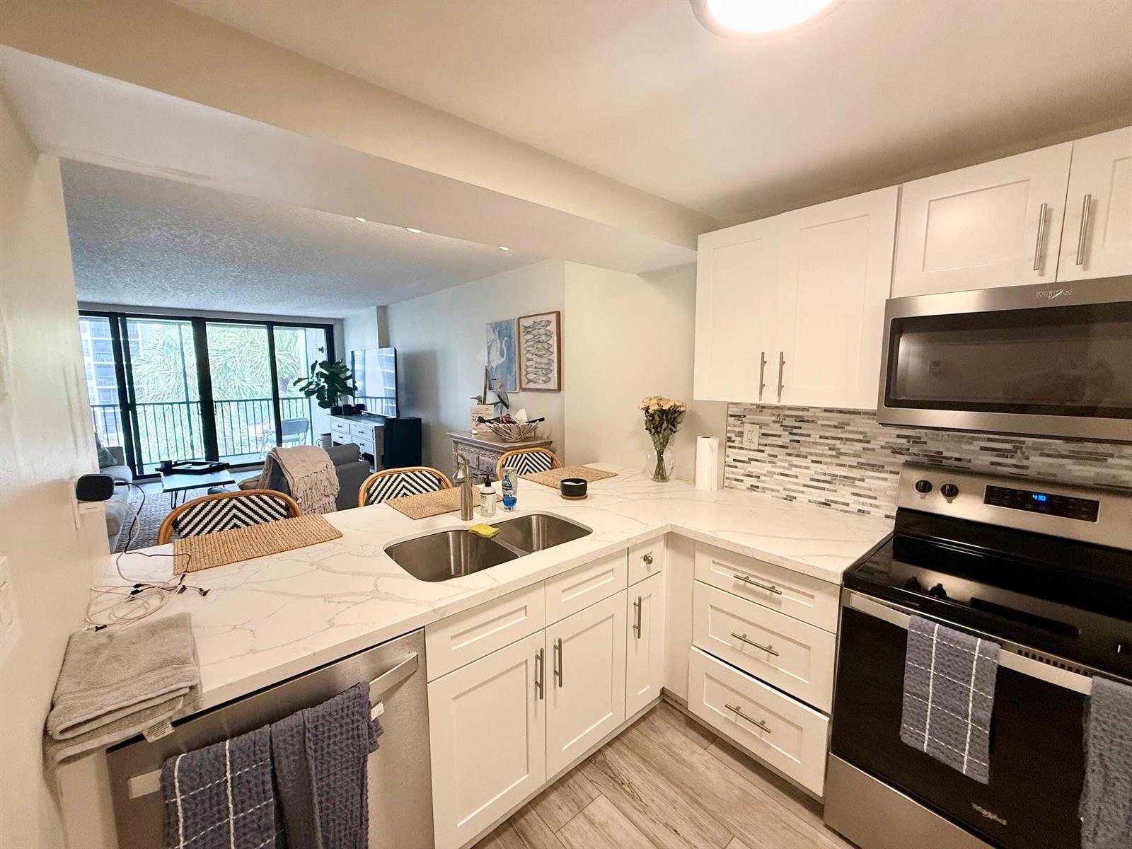 A kitchen with white cabinets, stainless steel appliances, and a quartz countertop peninsula — 11 Royal Palm Way # 303, Boca Raton FL 33432, BOCA RATON, FL