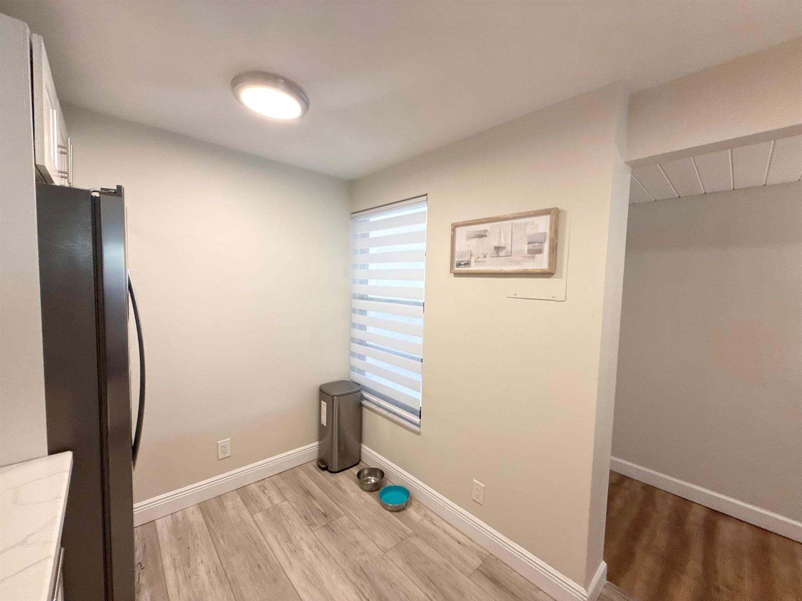 A kitchen corner features a stainless steel refrigerator, light wood-look flooring, and a window — 11 Royal Palm Way # 303, Boca Raton FL 33432, BOCA RATON, FL