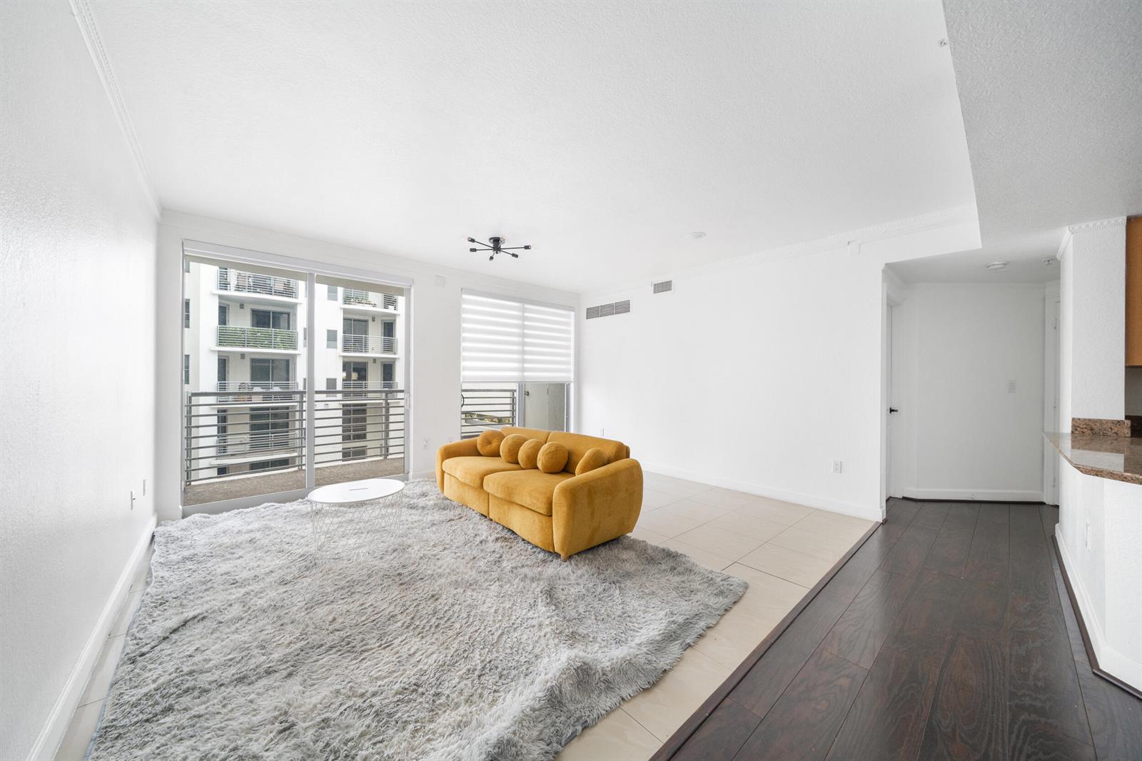 A living room features a yellow sofa, a gray shag rug, and a balcony view — 1830 Radius Drive # 405, Hollywood FL 33020, HOLLYWOOD, FL
