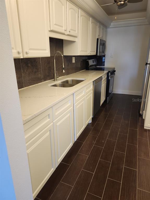 A kitchen with white cabinets, light countertops, dark tile backsplash, and dark wood-look flooring — 7400 SUN ISLAND DRIVE S UNIT 107, SOUTH PASADENA, FL