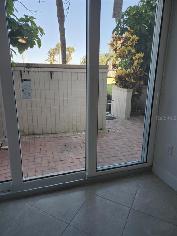 A view through sliding glass doors shows a brick patio with a low privacy wall — 7400 SUN ISLAND DRIVE S UNIT 107, SOUTH PASADENA, FL