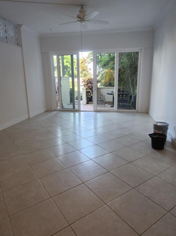 A living room with light tile flooring, a ceiling fan, and sliding glass patio doors — 7400 SUN ISLAND DRIVE S UNIT 107, SOUTH PASADENA, FL