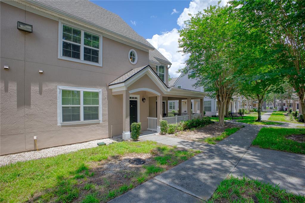 A two-story tan stucco townhouse with a covered front porch and a concrete walkway — 3433 SOHO STREET UNIT 202, ORLANDO, FL