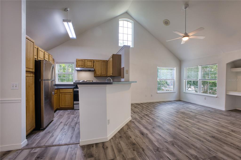 A kitchen with wood cabinets and stainless steel appliances opens to a living area — 3433 SOHO STREET UNIT 202, ORLANDO, FL