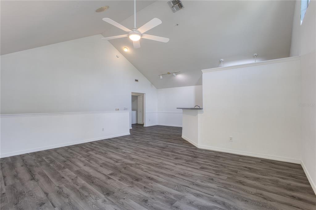 An empty room with vaulted ceilings, a ceiling fan, and gray wood-look flooring — 3433 SOHO STREET UNIT 202, ORLANDO, FL