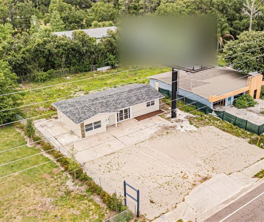 An aerial view shows a single-story house with a large gravel lot and a billboard — 4623 LAND O LAKES BOULEVARD, LAND O LAKES, FL