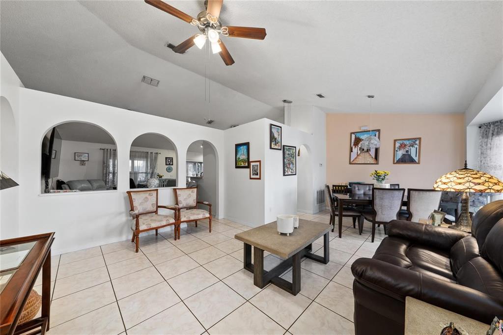 A living and dining area with tile floors, arched wall cutouts, and a ceiling fan — 22 BOLTON COURT, KISSIMMEE, FL