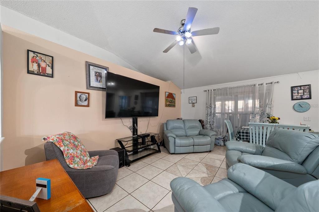 A living room with light-colored tile floors, a ceiling fan, and light blue leather furniture — 22 BOLTON COURT, KISSIMMEE, FL