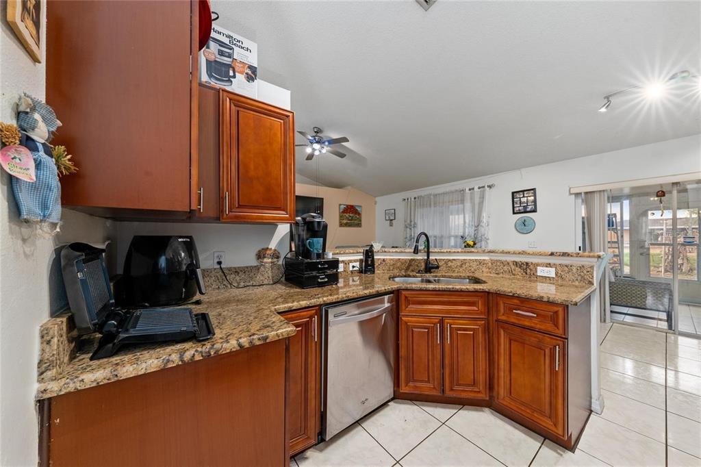 A kitchen with wood cabinets, granite countertops, stainless steel appliances, and tile flooring — 22 BOLTON COURT, KISSIMMEE, FL