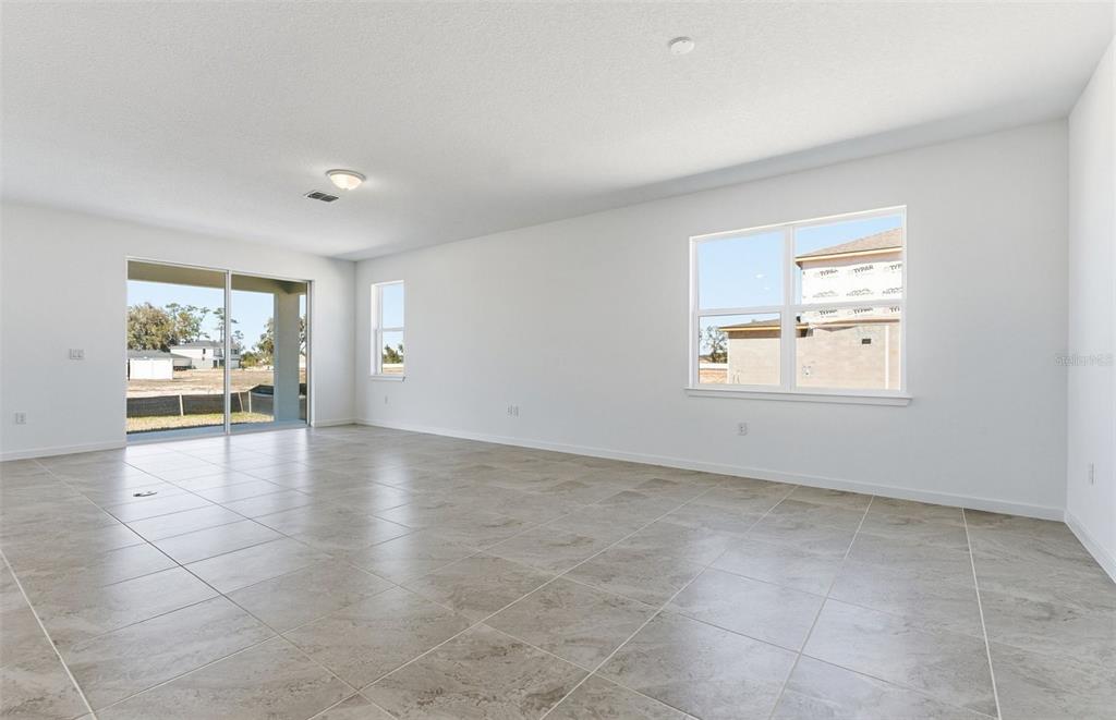 An empty room with white walls, large windows, a sliding glass door, and tiled flooring — 8132 SW 44TH COURT ROAD, OCALA, FL