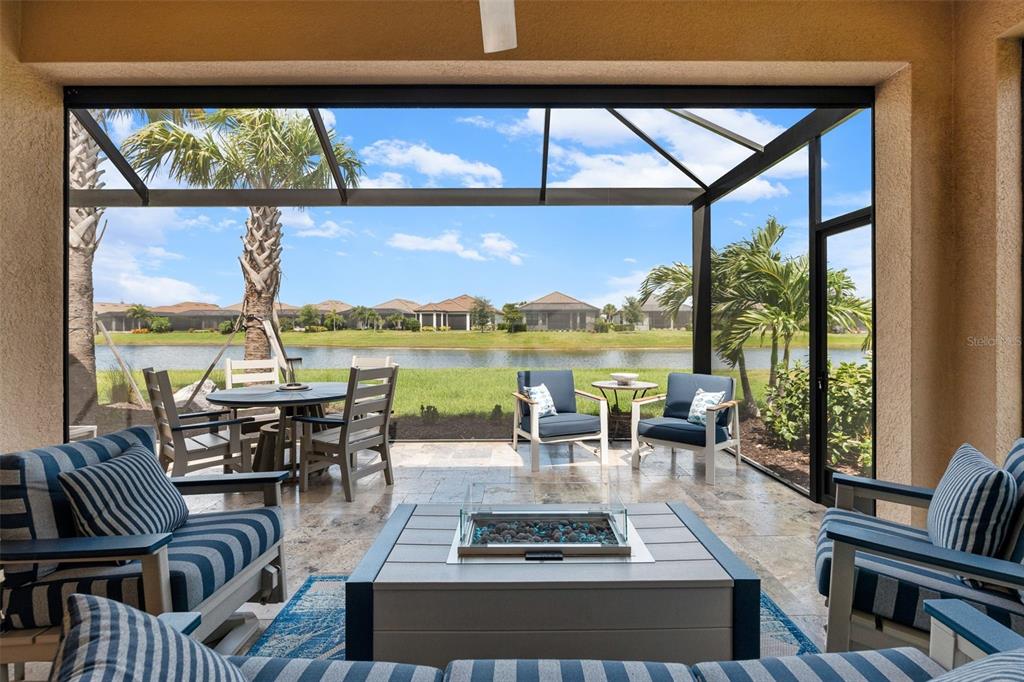A screened-in patio features a fire pit, outdoor seating, and a view of a lake — 3105 FORMIA COURT, BRADENTON, FL