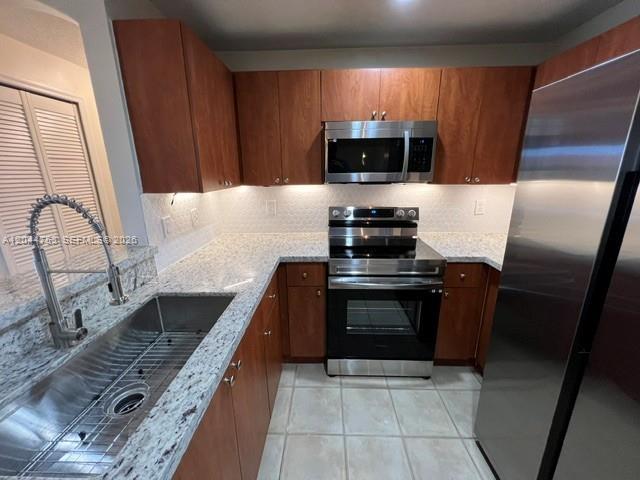 A kitchen features wood cabinets, stainless steel appliances, granite countertops, and a large metal sink — 6360 NW 114th Ave # 233, Doral FL 33178, DORAL, FL
