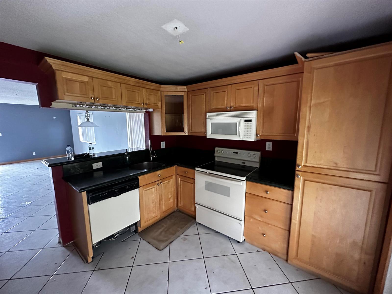 A kitchen features light wood cabinets, black countertops, white appliances, and a tiled floor — 3777 NW 78th Avenue # 6a, Davie FL 33024, DAVIE, FL