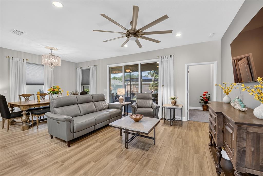 A living room with wood-look tile flooring, a gray sofa, and a ceiling fan — 3508 NW 55TH COURT, OCALA, FL