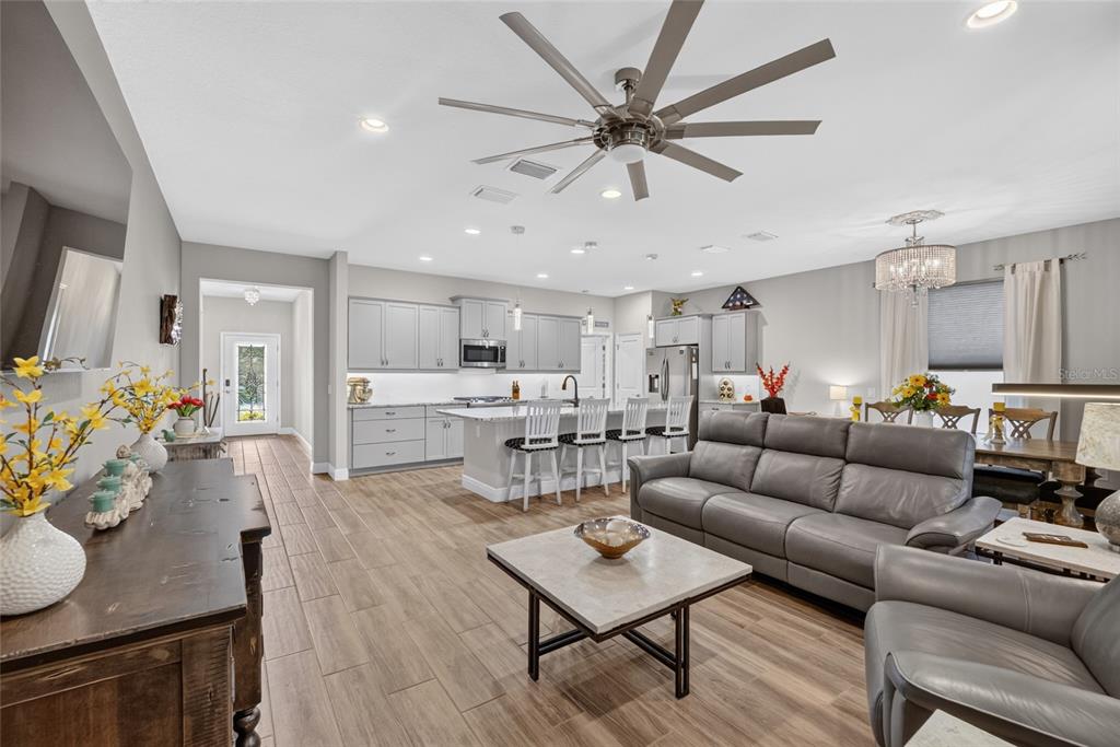 An open-concept living room and kitchen feature gray cabinetry, a large island, and wood-look flooring — 3508 NW 55TH COURT, OCALA, FL