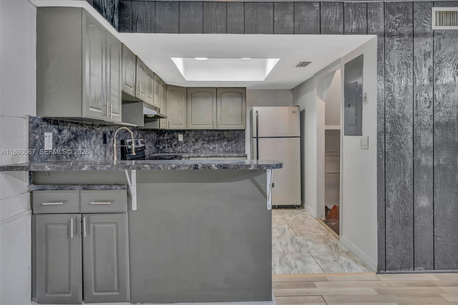 A kitchen features gray cabinets, a marble-patterned countertop, and a breakfast bar — 94 Pleasant Hill Ln, Tamarac FL 33319, TAMARAC, FL