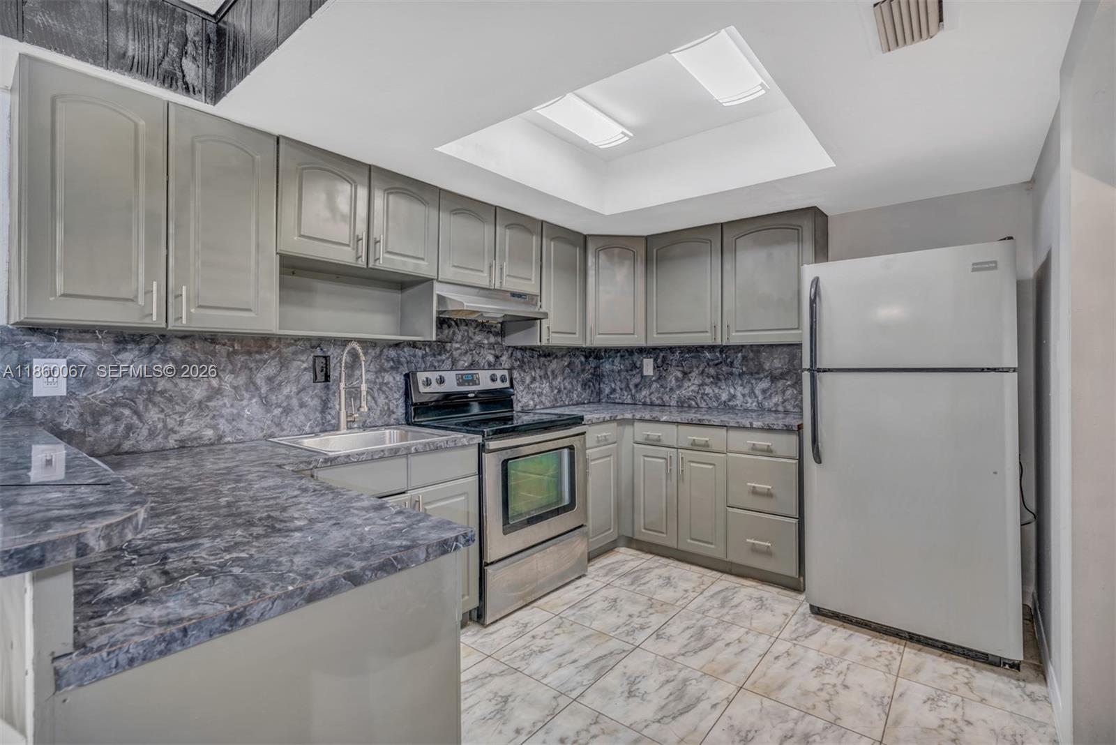 A kitchen features gray cabinets, dark marble-patterned countertops, stainless steel appliances, and tiled flooring — 94 Pleasant Hill Ln, Tamarac FL 33319, TAMARAC, FL