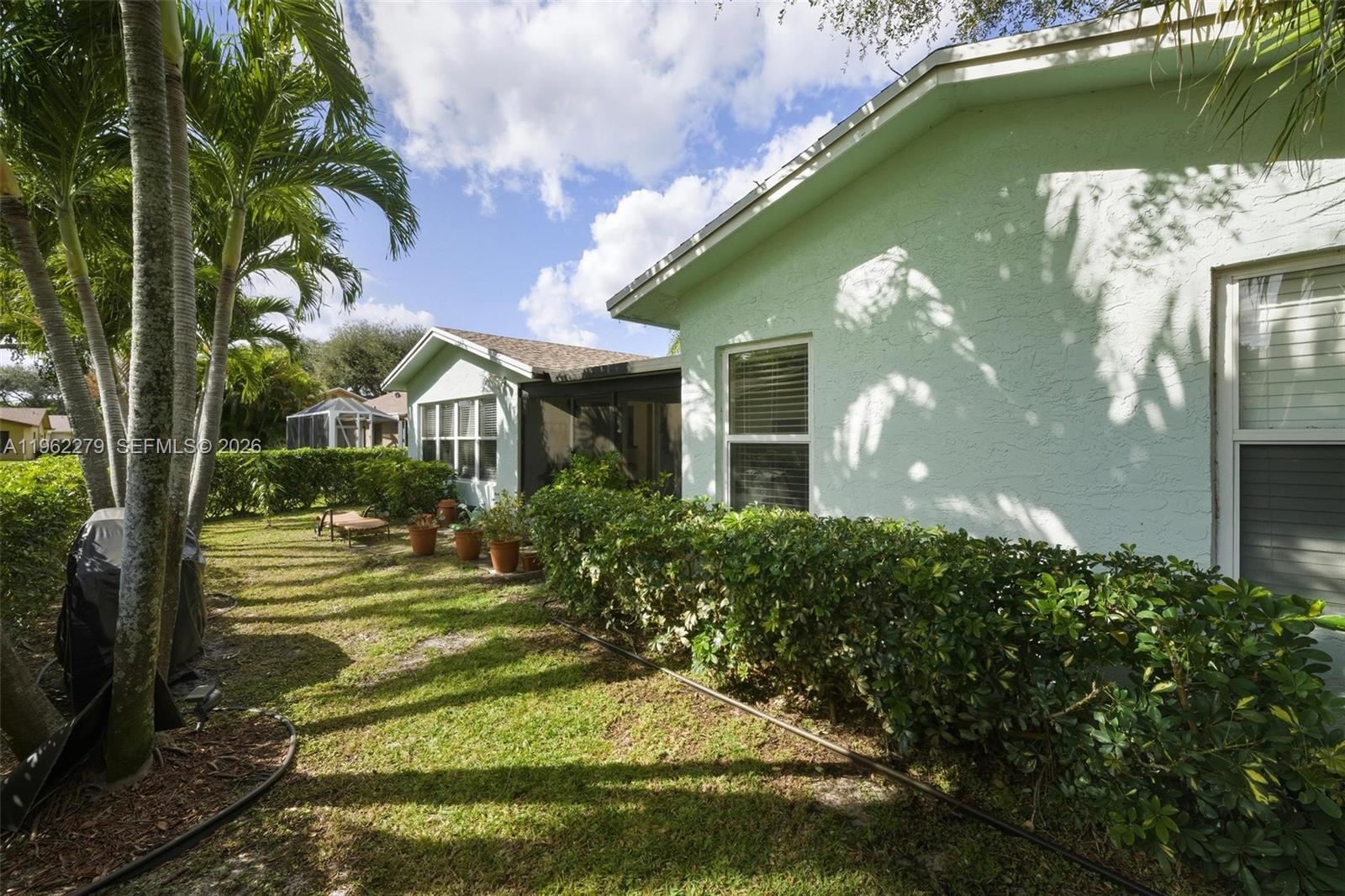 A light green house exterior features a screened-in patio and a landscaped backyard — 10308 Greenbriar Ct, Boca Raton FL 33498, BOCA RATON, FL