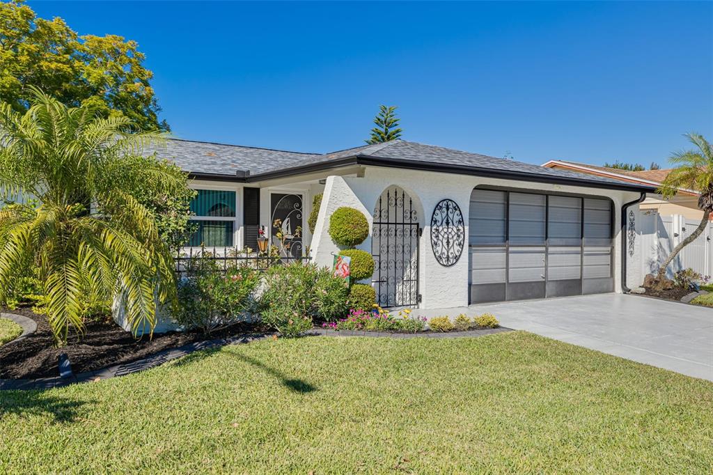 A white single-story house with a gray shingled roof, a garage, and a palm tree — 7239 VIENNA LANE, PORT RICHEY, FL