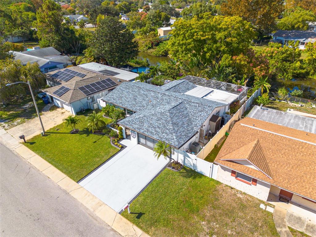 An aerial view shows a suburban house with a gray shingled roof and solar panels — 7239 VIENNA LANE, PORT RICHEY, FL