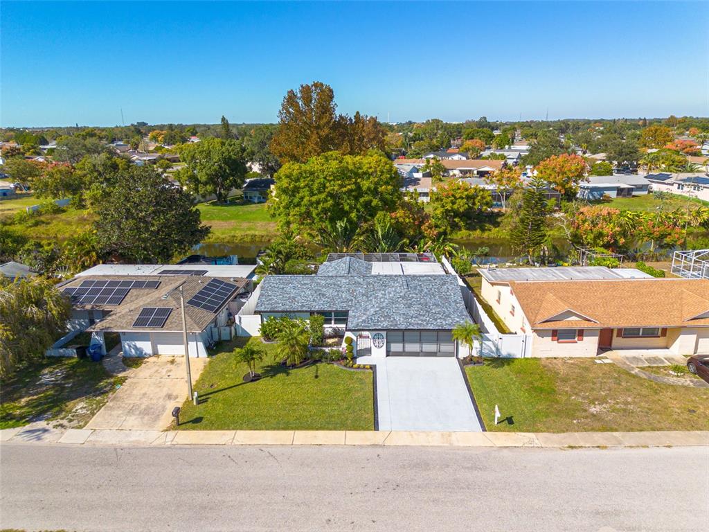 An aerial view shows a suburban house with a gray roof, driveway, and solar panels — 7239 VIENNA LANE, PORT RICHEY, FL