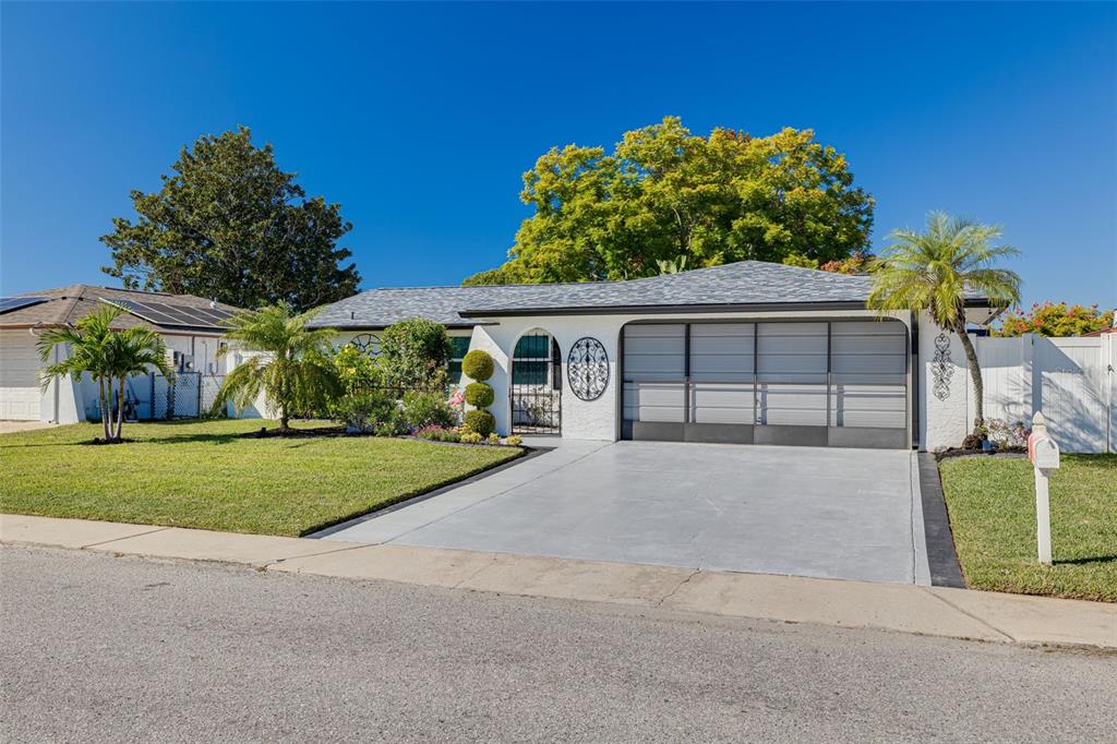 A single-story white house with a gray roof, a concrete driveway, and a garage — 7239 VIENNA LANE, PORT RICHEY, FL