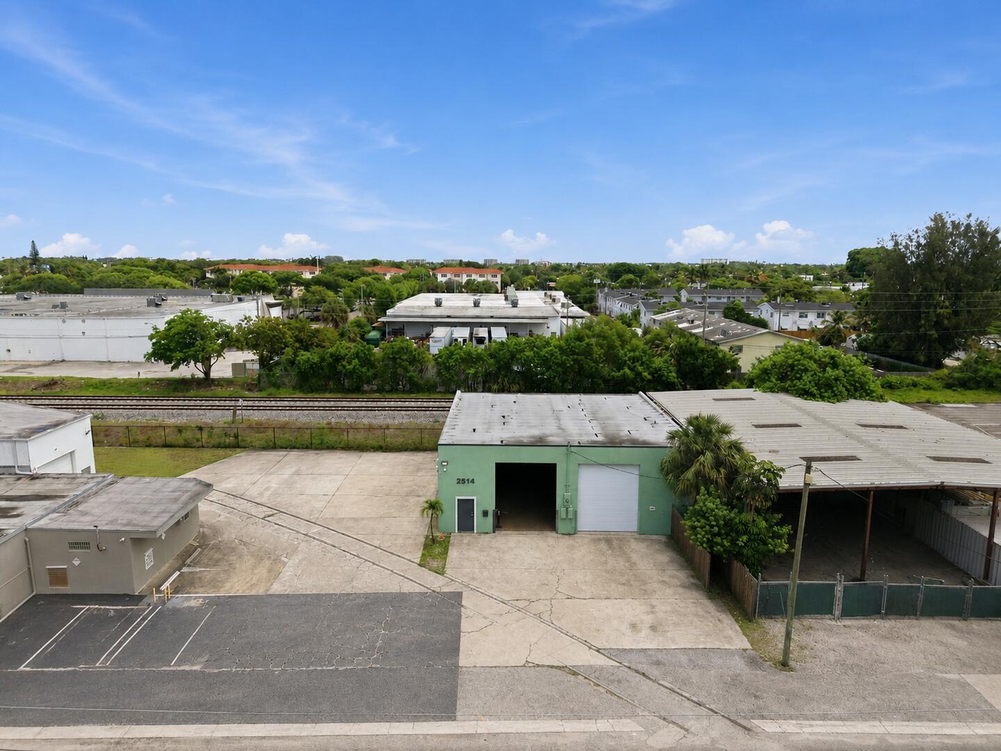 An aerial view shows a green industrial building with a concrete lot and railroad tracks — 2514 Park Street, FL 33460, FL