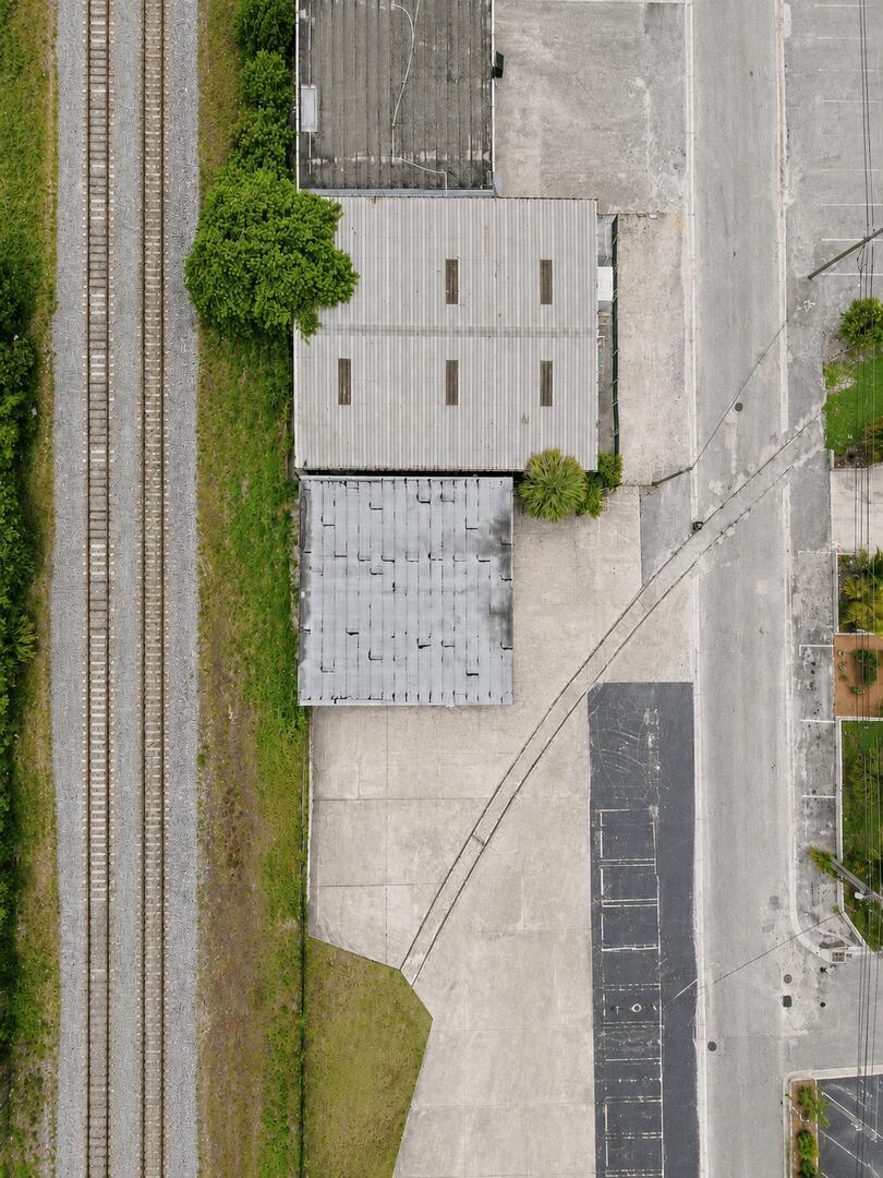 An aerial view shows two industrial buildings next to railroad tracks and a paved lot — 2514 Park Street, FL 33460, FL