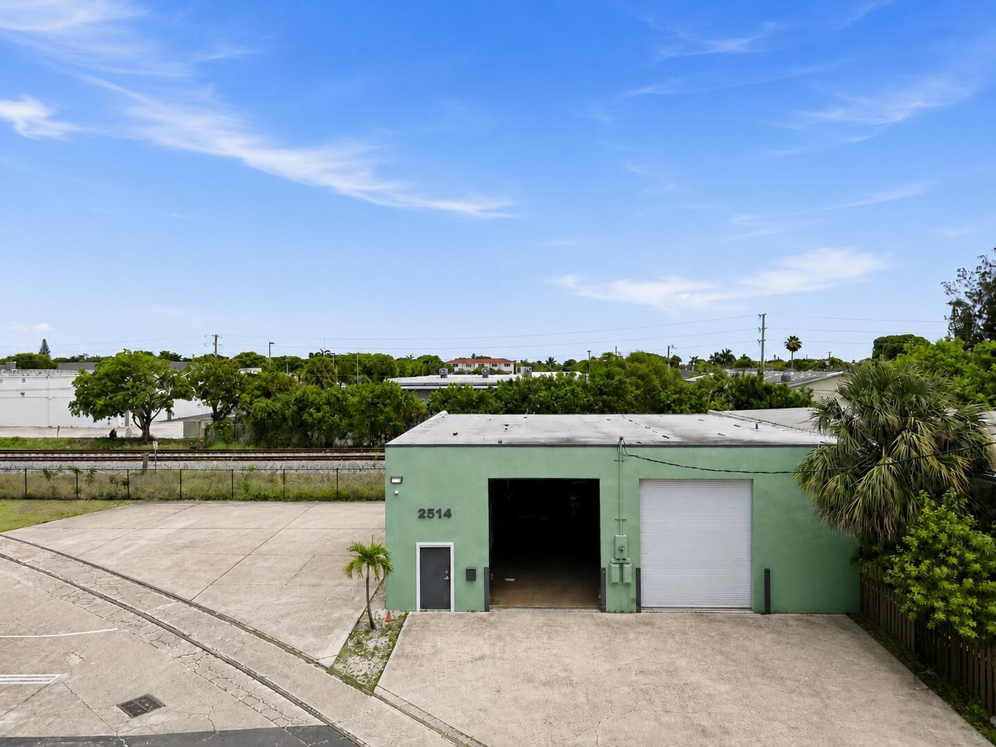 An aerial view of a green industrial building with a roll-up door and parking lot — 2514 Park Street, FL 33460, FL