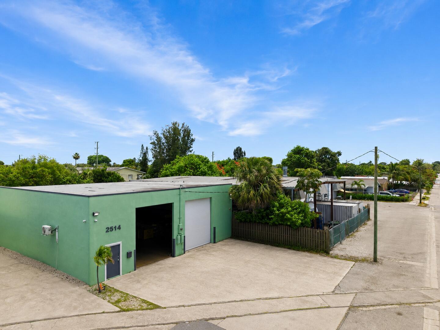 An aerial view of a green industrial building with two garage doors and a fence — 2514 Park Street, FL 33460, FL
